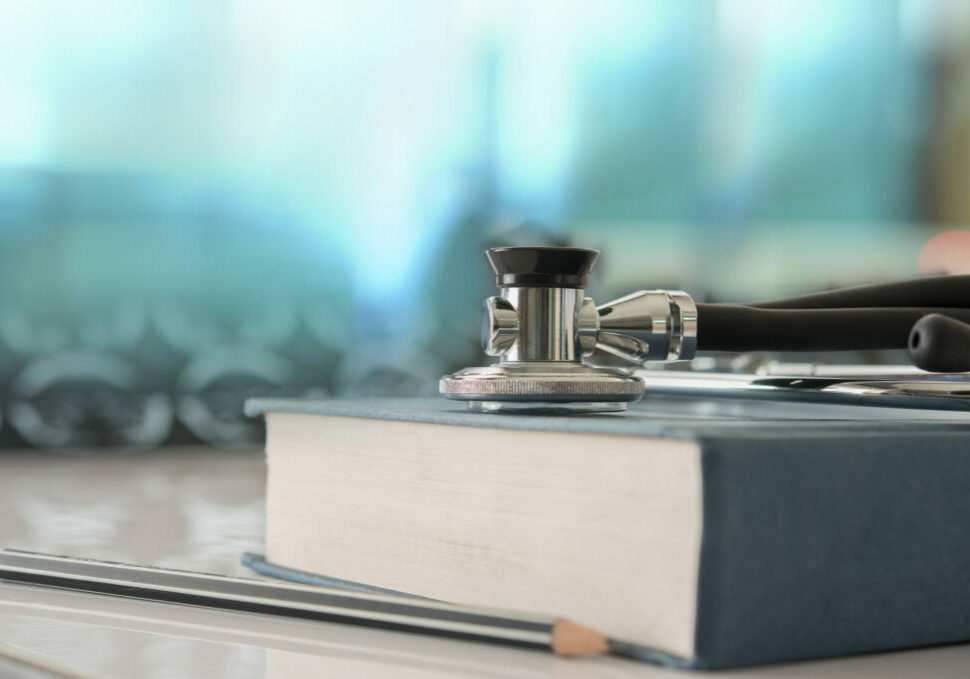 healthcare and medicine concept. Stethoscope with medical text book on doctor student desk at classroom in the hospital.